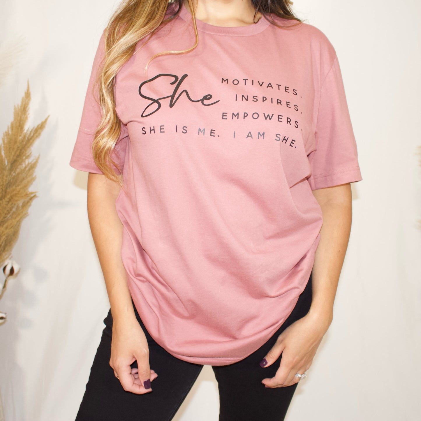 front side, close up of a t-shirt with wording saying She motivated, inspires, empowers, she is me, i am she in t-shirt color mauve