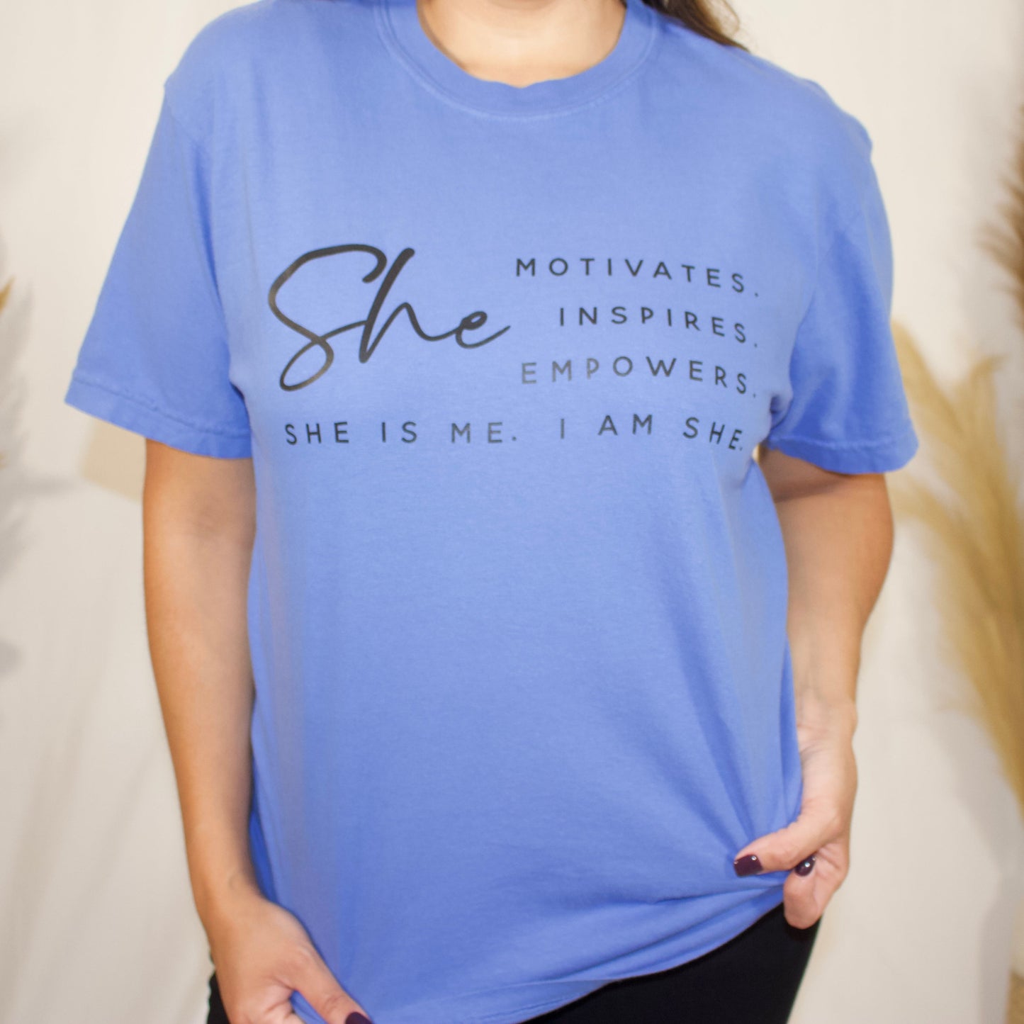 front side, close up of a t-shirt with wording saying She motivated, inspires, empowers, she is me, i am she in t-shirt color mystic blue