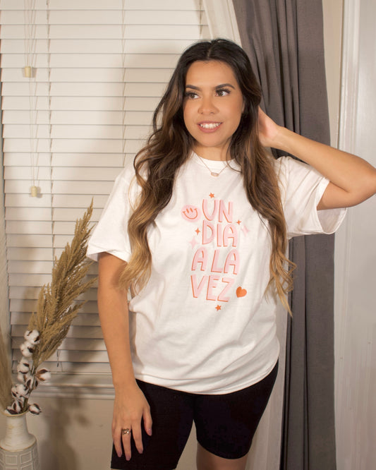 pink and red print letters on a white t-shirt, un dia  a la vez