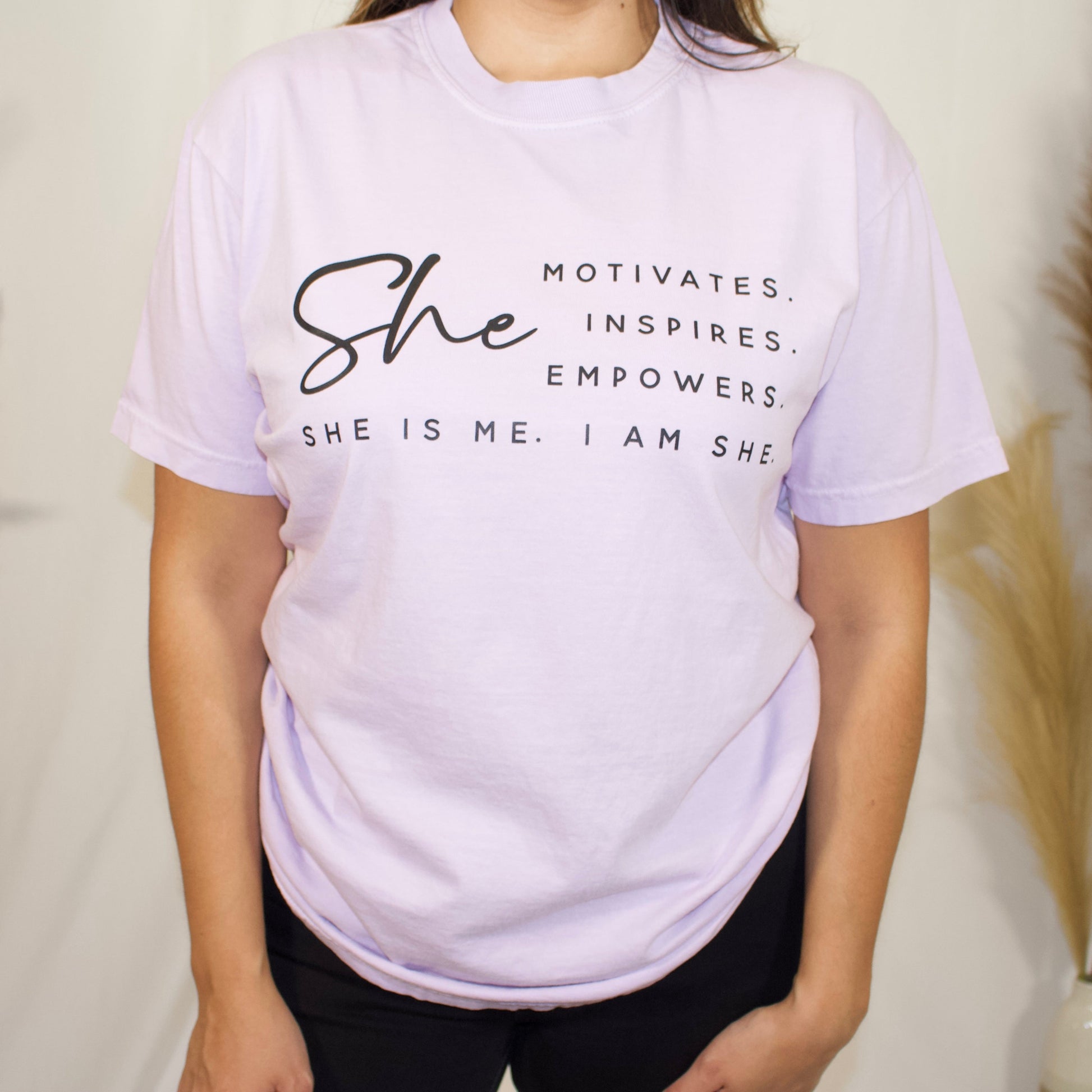 front side, close up  of a t-shirt with wording saying She motivated, inspires, empowers, she is me, i am she in t-shirt color lilac