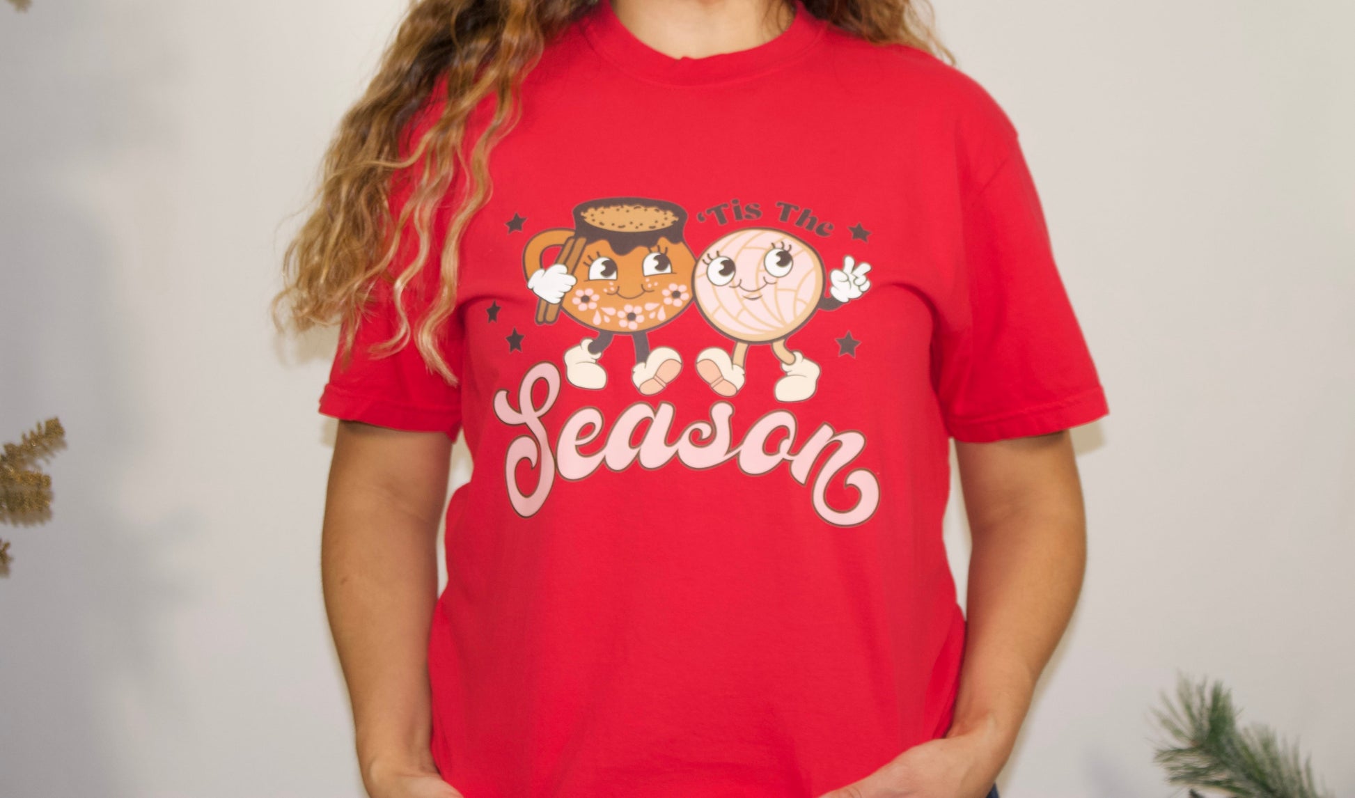 RED T SHIRT FRONT SIDE WITH PINK LETTERS AND BROWN LETTER THAT SAYS TIS THE SEASON WITH A PINK CONCHA AND A MEXICAN JARRO CLOSE UP